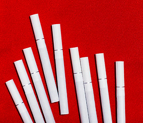 Image showing scattered white cigarettes on red background