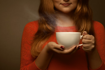 Image showing woman holding hot cup and smiles