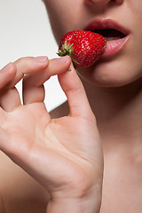 Image showing Young woman biting strawberry isolated on white