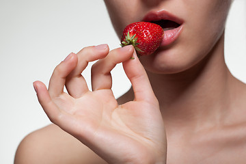 Image showing Young woman biting strawberry isolated on white