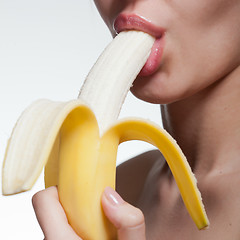 Image showing Young woman biting banana isolated on white