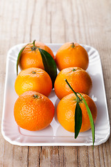 Image showing tangerines with leaves in plate