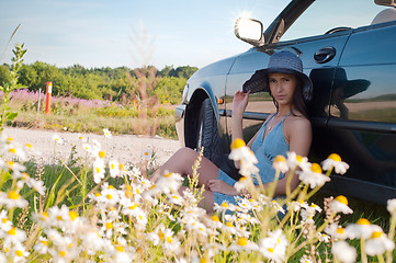 Image showing Beautiful brunette woman sitting near car