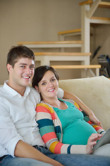 Image showing pregnant couple at home using tablet computer