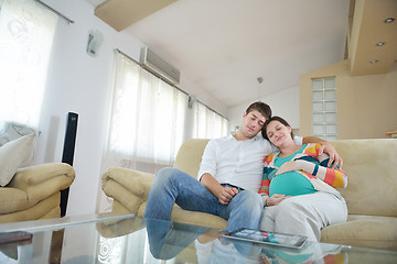 Image showing pregnant couple at home using tablet computer