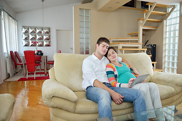 Image showing pregnant couple at home using tablet computer