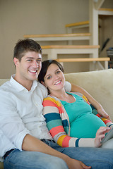 Image showing pregnant couple at home using tablet computer