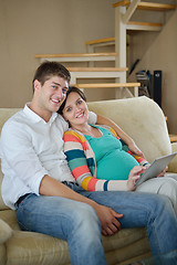 Image showing pregnant couple at home using tablet computer