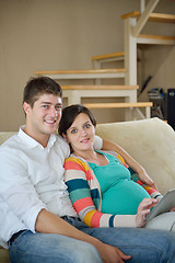 Image showing pregnant couple at home using tablet computer