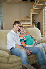 Image showing pregnant couple at home using tablet computer