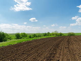 Image showing black plowed field and blue sky with clouds