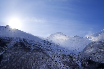 Image showing Snowy mountains in haze and sky with sun, view from off piste sl