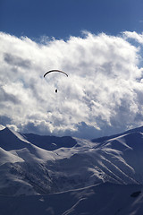 Image showing Winter mountain with clouds and silhouette of parachutist