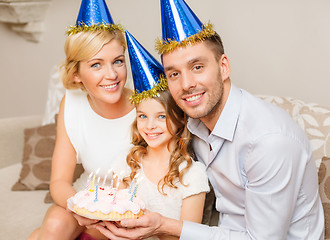 Image showing smiling family in blue hats with cake