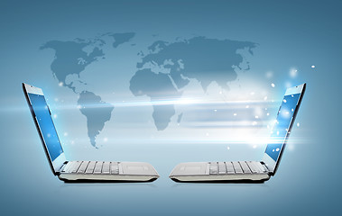 Image showing two laptop computers with world map hologram