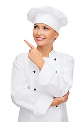 Image showing smiling female chef pointing finger to sonething