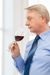 Image showing older man smelling red wine