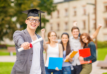 Image showing smiling teenage boy in corner-cap with diploma