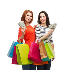 Image showing smiling teenage girls with shopping bags and money