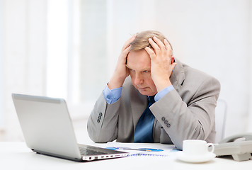 Image showing upset older businessman with laptop and telephone