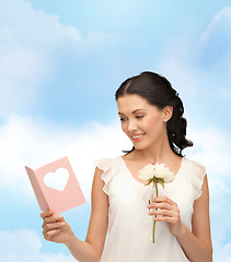 Image showing young woman holding flower and postcard