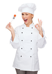 Image showing smiling female chef with fork and tomato