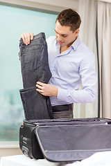 Image showing businessman packing things in suitcase