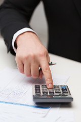 Image showing close up of businessman with papers and calculator