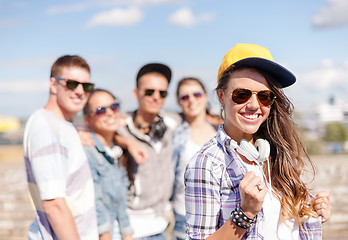 Image showing teenage girl with headphones and friends outside