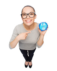 Image showing woman in eyeglasses pointing finger to blue clock