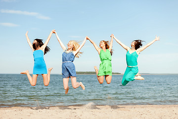 Image showing smiling girls jumping on the beach