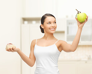 Image showing sporty woman with apple and cake in kitchen