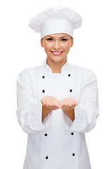 Image showing smiling female chef holding something on hands