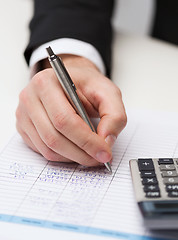 Image showing close up of businessman with papers and calculator