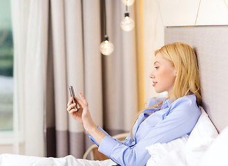 Image showing happy businesswoman with smartphone in hotel room