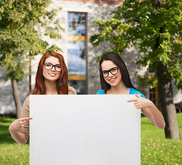 Image showing two smiling girls with eyeglasses and blank board