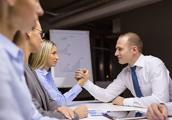 Image showing businesswoman and businessman arm wrestling