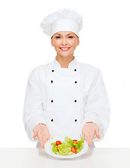 Image showing smiling female chef with salad on plate