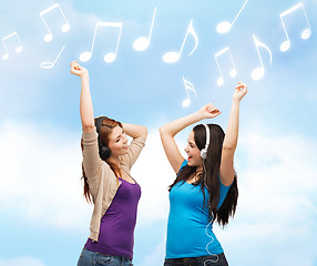 Image showing two laughing girls with headphones dancing