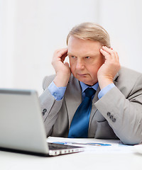 Image showing upset older businessman with laptop in office