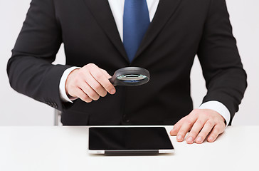 Image showing businessman hand holding magnifier over tablet pc