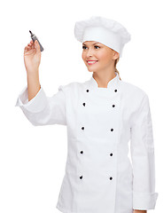 Image showing smiling female chef writing something on air