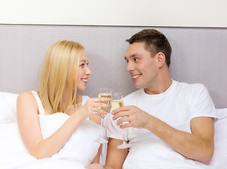 Image showing smiling couple with champagne glasses in bed