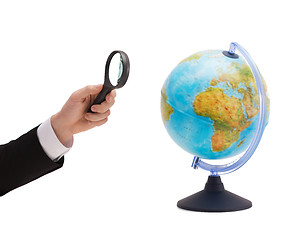 Image showing businessman hand holding magnifier over globe