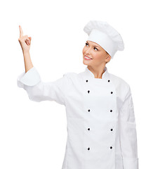 Image showing smiling female chef pointing finger to sonething