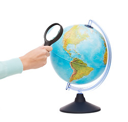 Image showing woman hand holding magnifying glass over globe