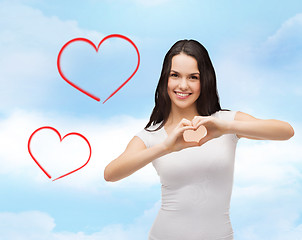 Image showing smiling girl showing heart with hands