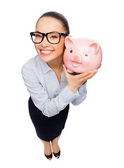 Image showing happy businesswoman in eyeglasses with piggy bank