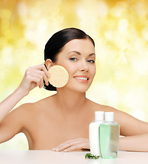 Image showing smiling woman with sponge and cosmetic bottles