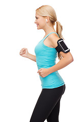 Image showing sporty woman running with smartphone and earphones